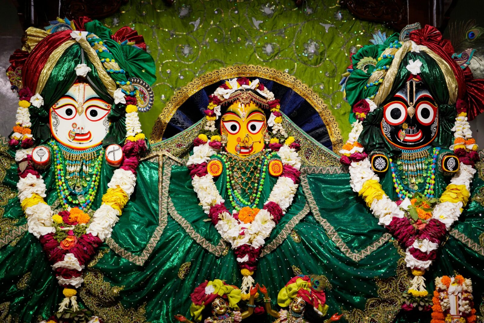 Vibrant deity sculptures adorned with flowers in ISKCON Bangladesh Temple.